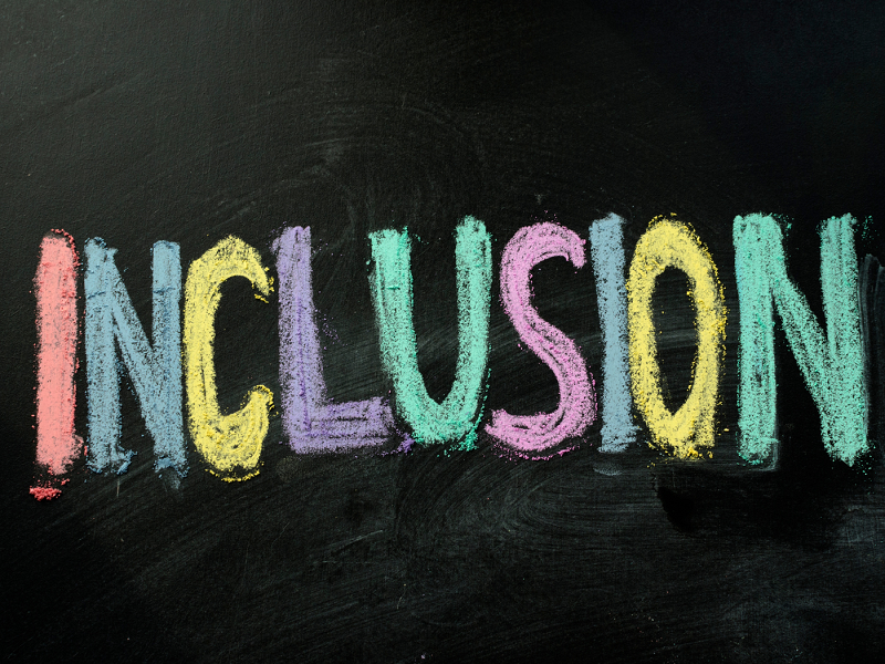 The word 'inclusion' written in coloured chalk on a blackboard